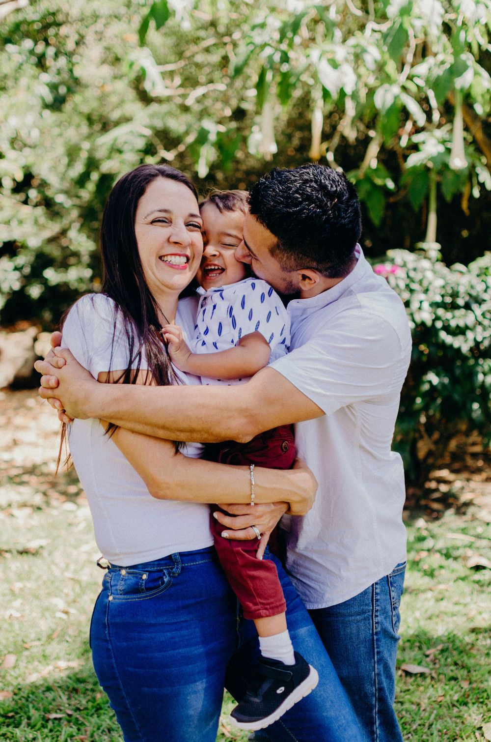 A heartwarming family embrace filled with laughter in a sunny garden setting.
