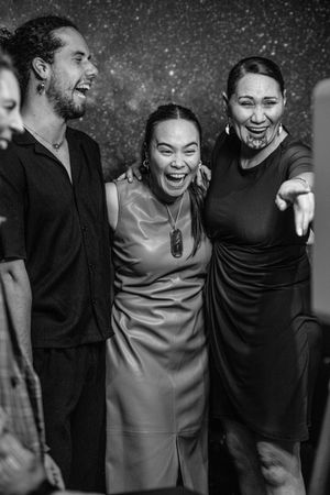 Three joyful friends laughing and posing together at a formal event in black and white photo.