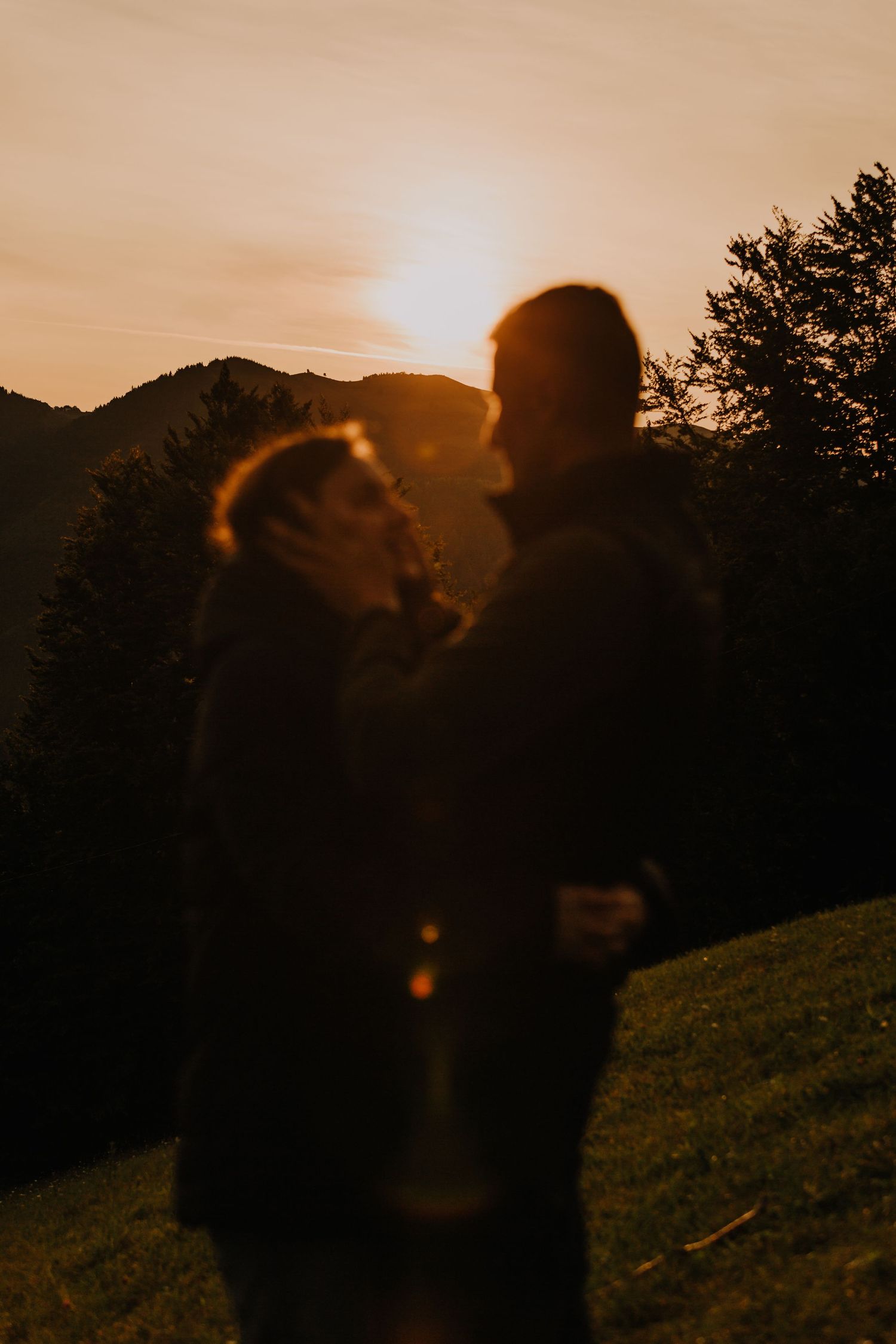 Bride and groom share romantic moment in golden sunset light surrounded by lush green forest.