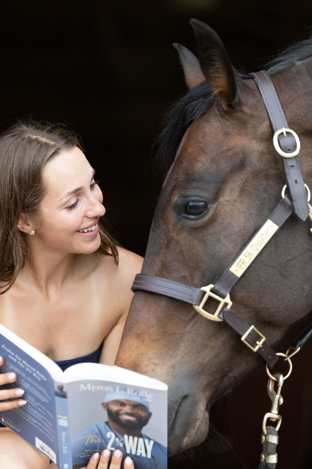 girl holding college textbook with horse looking over her shoulder
