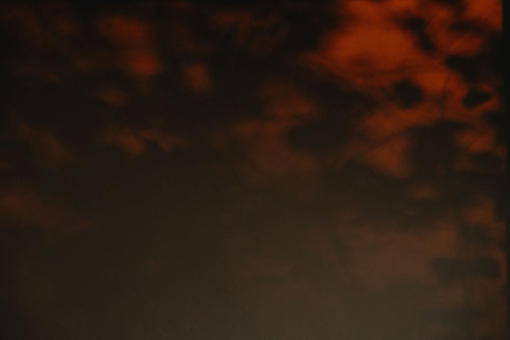 Dark moody sky with dramatic red-orange clouds at dusk, creating an ominous atmospheric sunset backdrop.