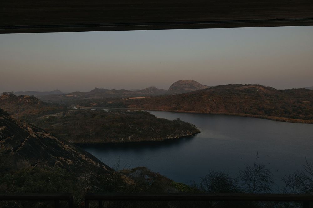 Scenic twilight view of a tranquil lake surrounded by rocky hills and mountains at dusk.