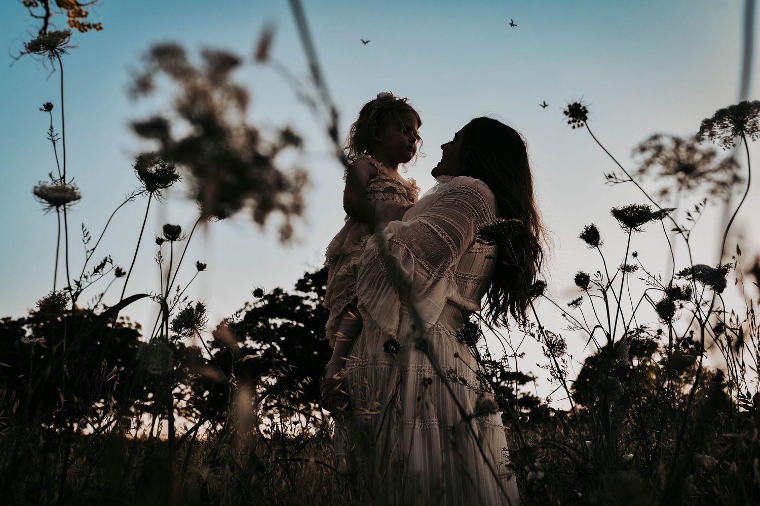 a silhouette of a mother and daughter playing in the flowers at white rock lake