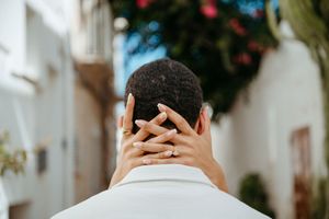 A woman tenderly places her hands on a man's head in a romantic Mediterranean alleyway.
