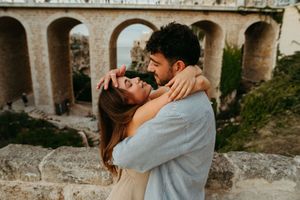 Romantic couple embracing and almost kissing with ancient stone arches in the background.