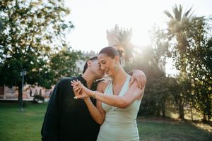 Couple sharing a tender moment admiring an engagement ring in a sunlit park.