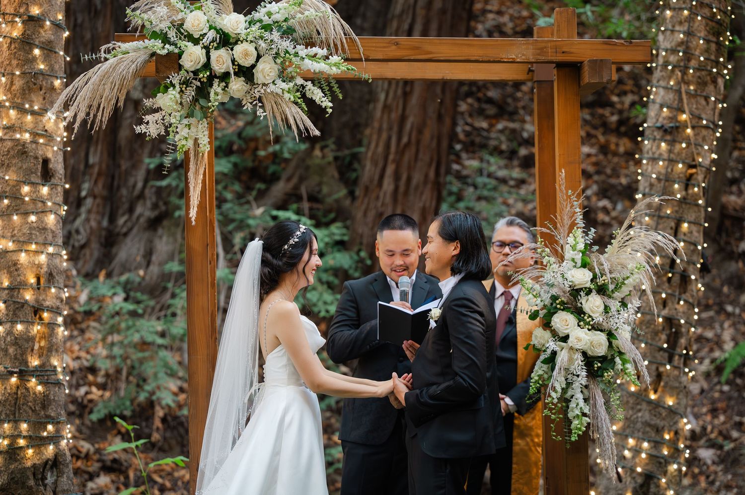 Bride and groom pose in front of cactus garden with golden mountain backdrop at outdoor wedding.