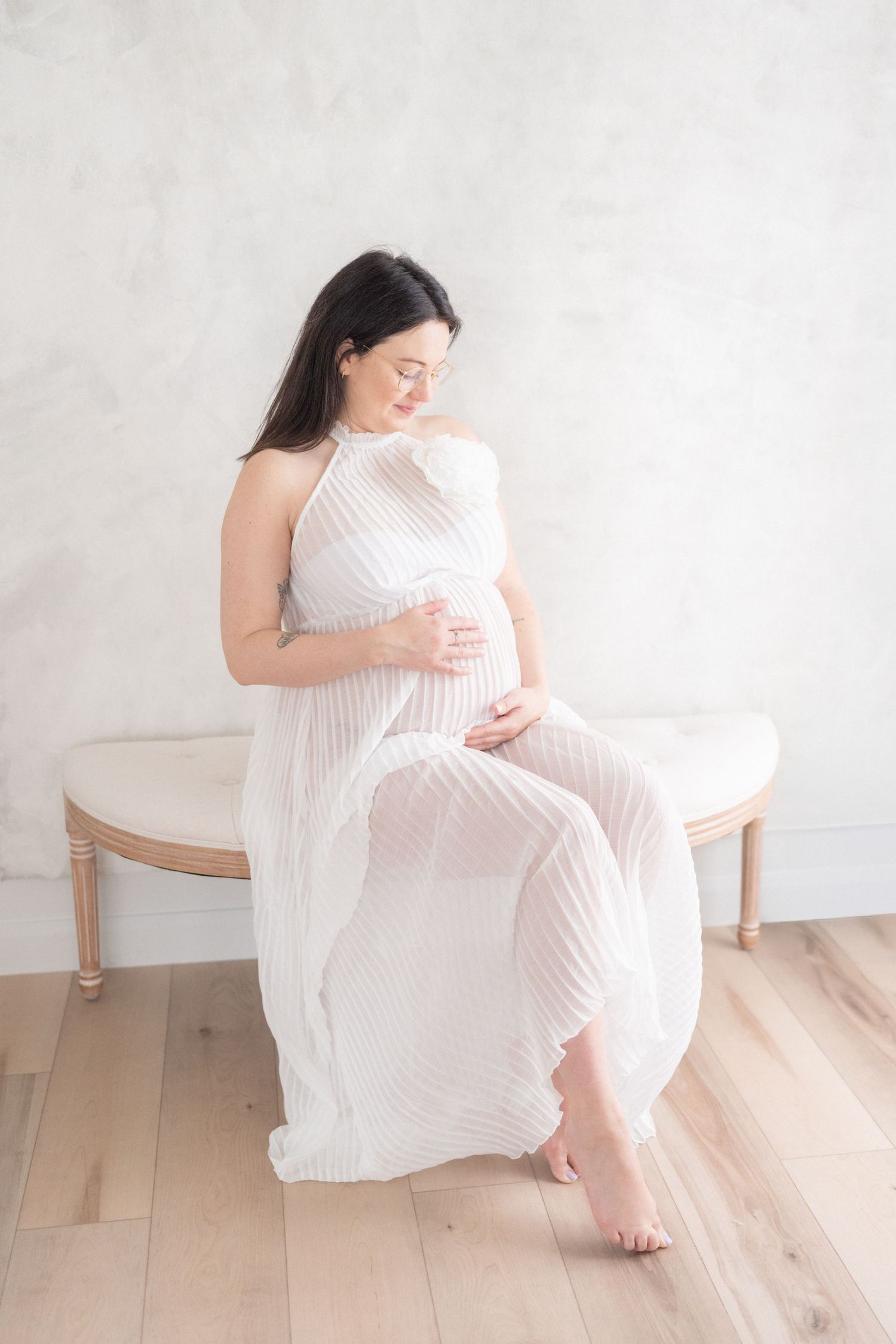 future maman en robe blanche et diaphane adorant son ventre rond de ses mains délicatement posées