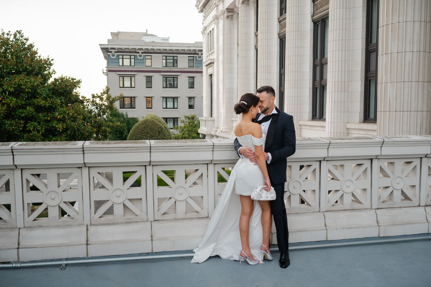 Elegant wedding ceremony at San Francisco City Hall, couple standing on grand marble staircase rotunda with seated guests.