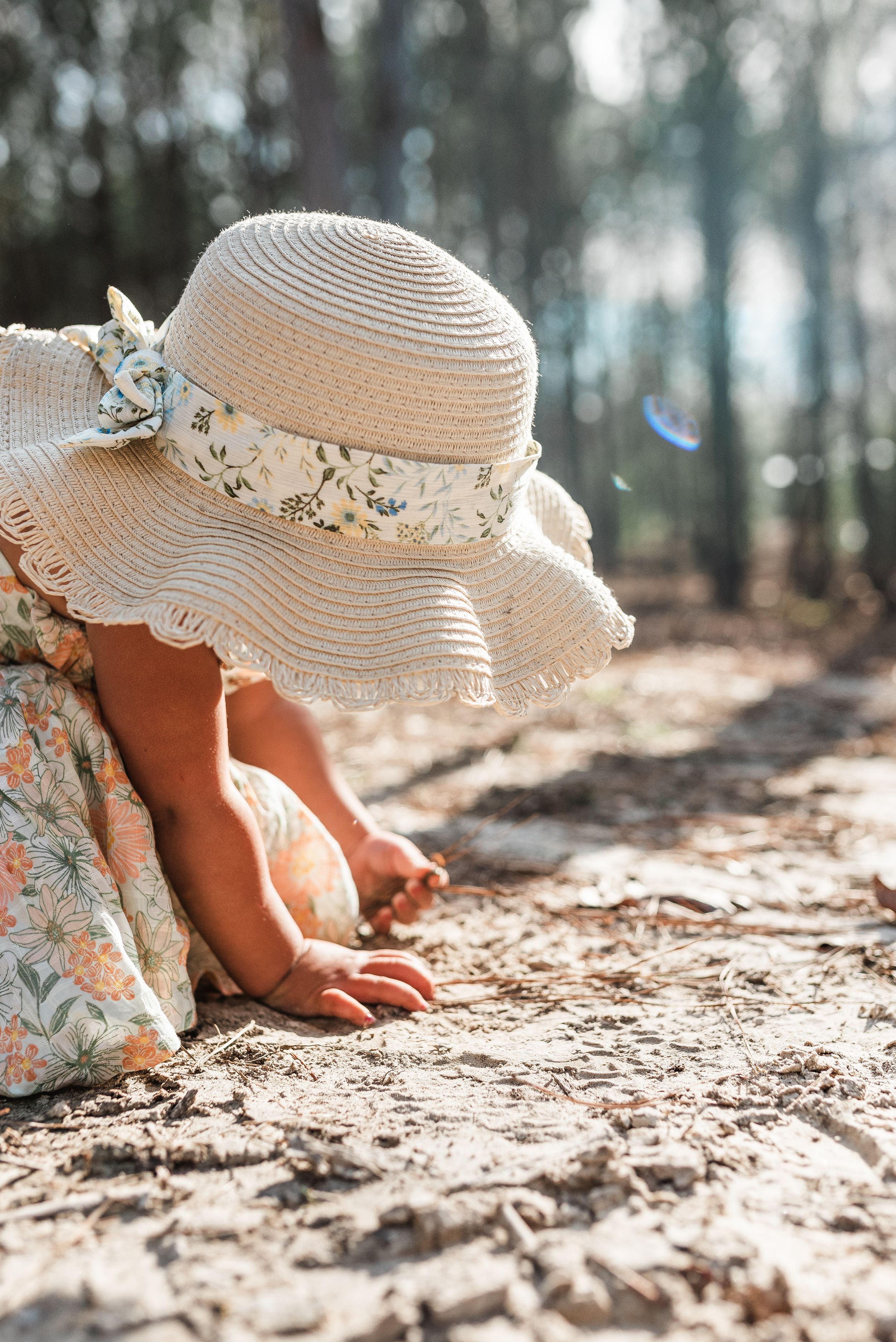 child in hat playing in dirt