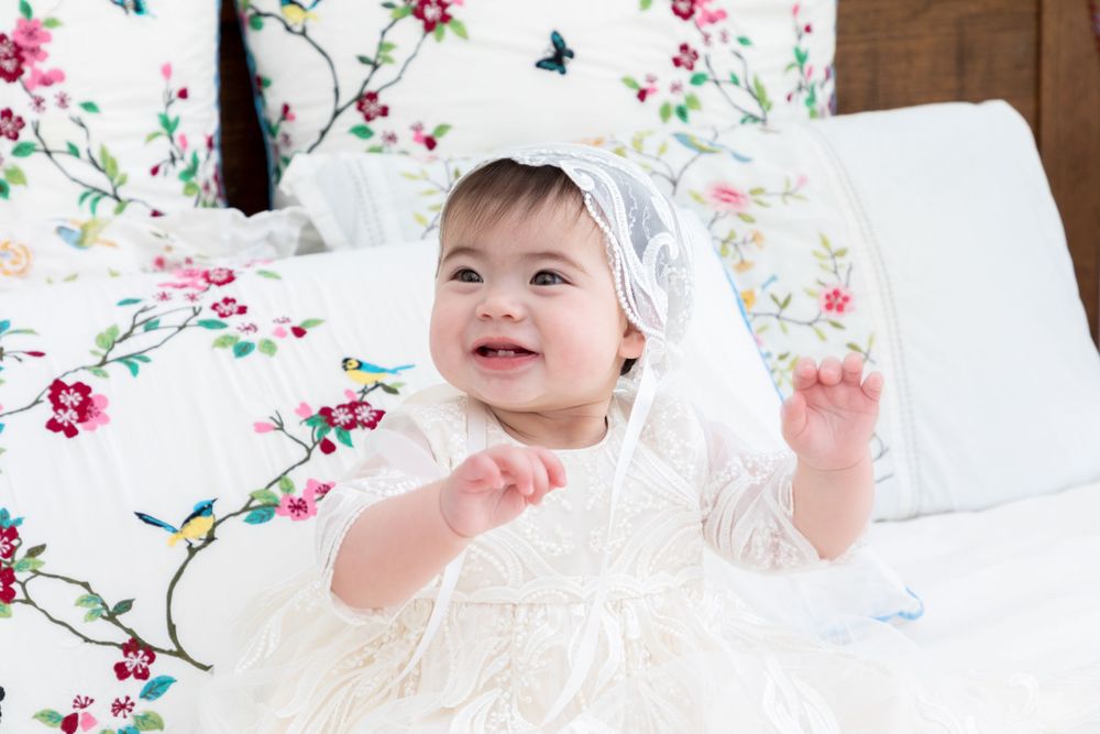 baby on christening on bed wearing christening gown