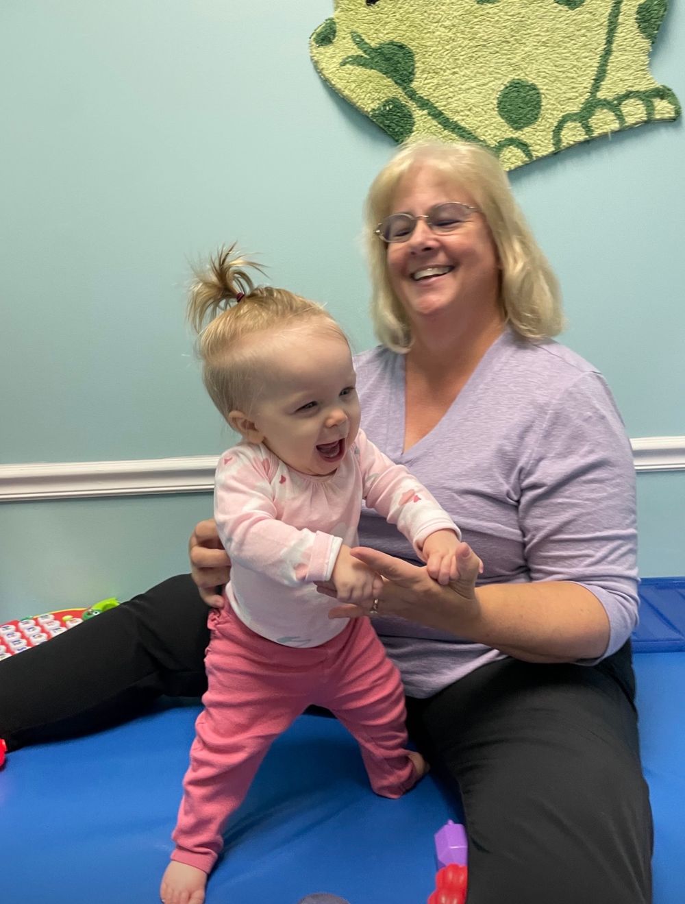 A joyful moment shared between two people in a playroom with a decorated crown on the wall behind them.