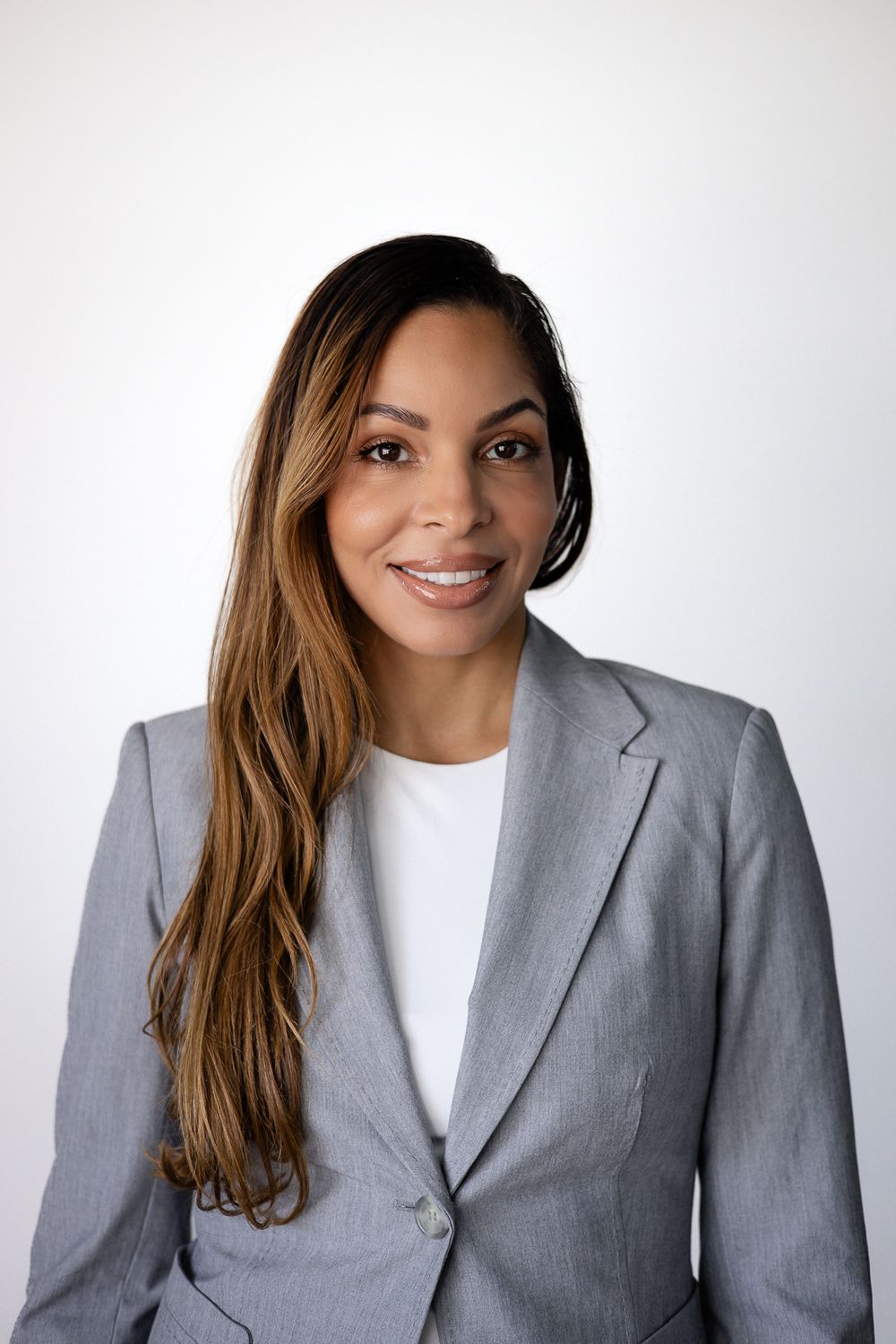 Woman in gray suit smiling for professional corporate headshot, Miami LinkedIn portrait by Mannyportraits for executives.