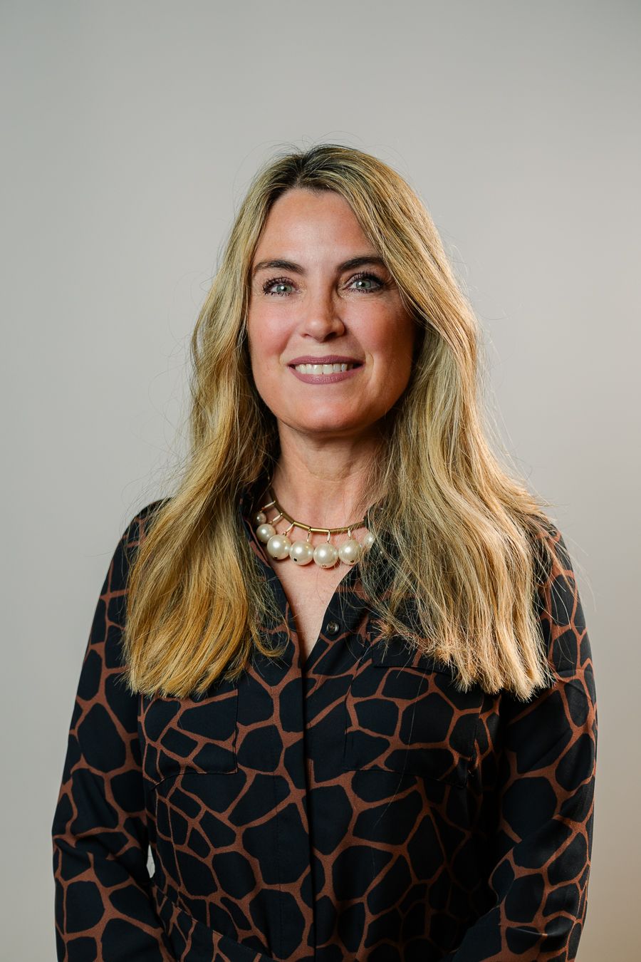 Confident woman with long blonde hair in patterned blouse, Miami corporate headshot by Mannyportraits.