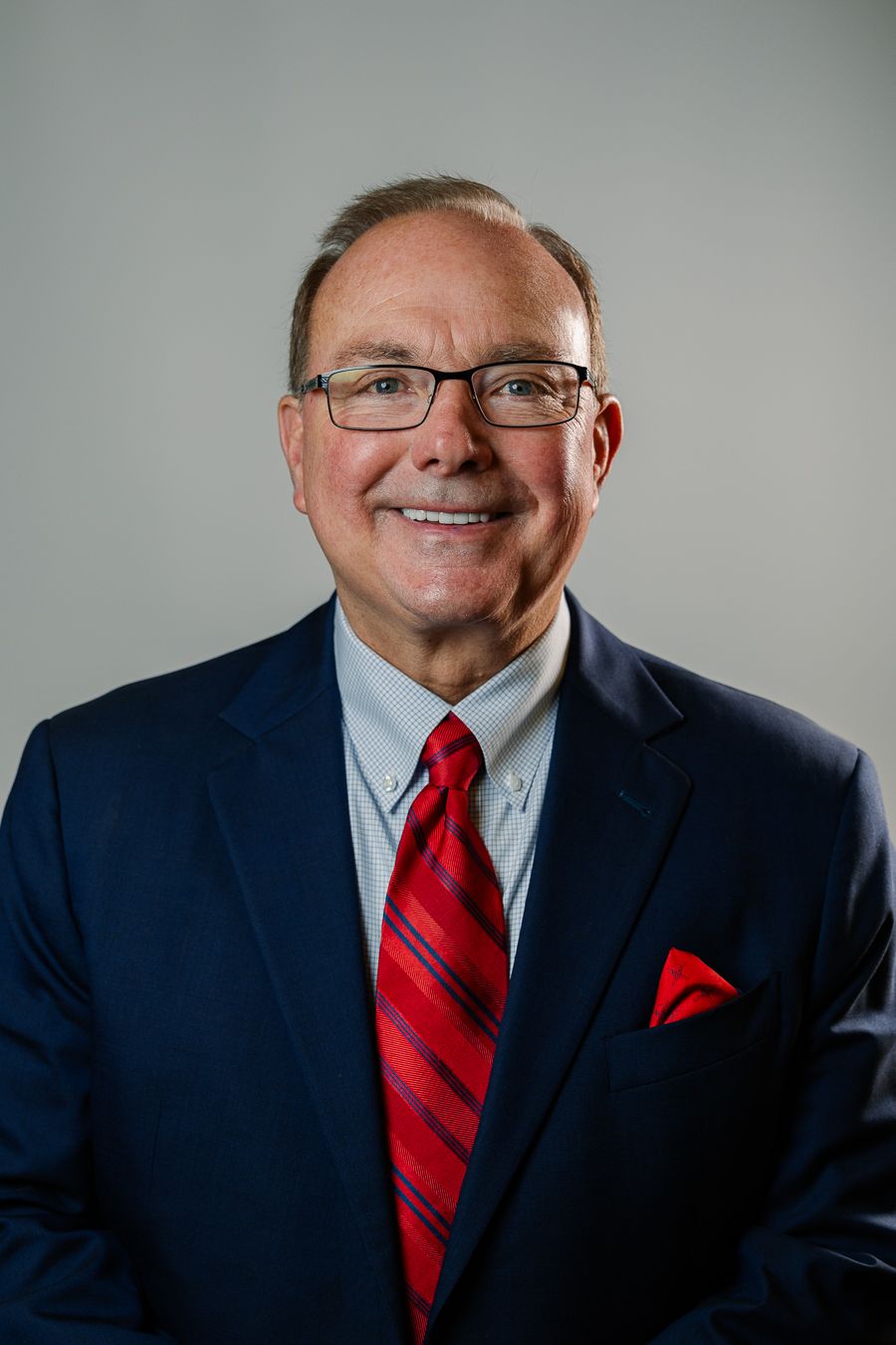Smiling man in red tie and suit, Miami executive headshot by Mannyportraits, ideal for lawyers, doctors, and corporate leaders.