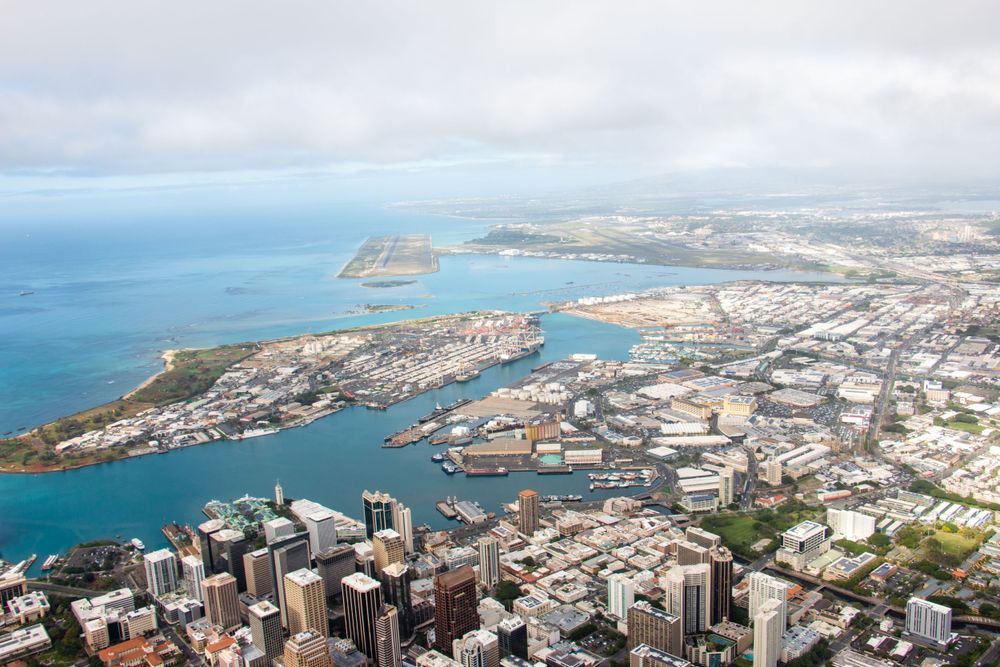 Aerial view of Honolulu Harbor and downtown skyline with Pacific Ocean and mountains in Hawaii.