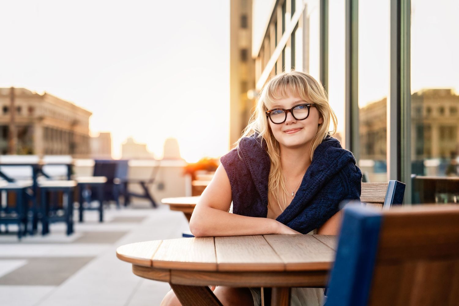 Senior photo of a girl with her sweater over her shoulders sitting on a roof deck taken by Milwaukee senior photographer Rachel Dickman.