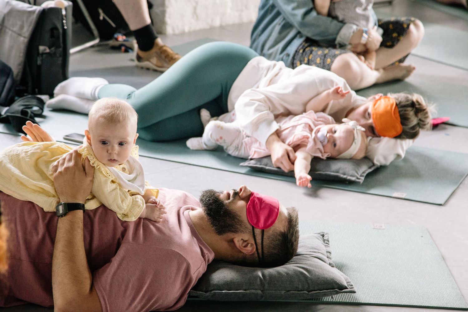 Parents and babies practicing yoga together on mats during a mommy and me fitness class.