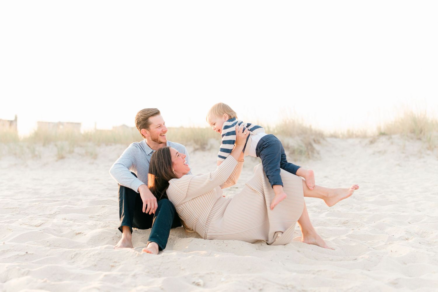 A mother lifts her son in the air while laying on the beach in sea girt nj.
