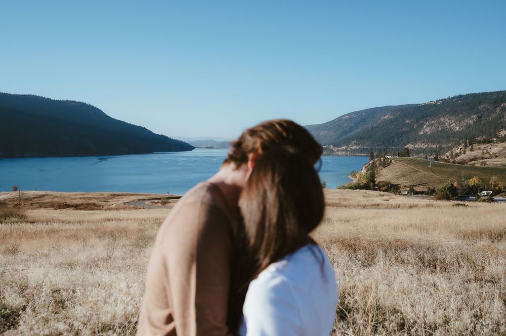 Couple silhouetted against scenic lake and mountain landscape view.