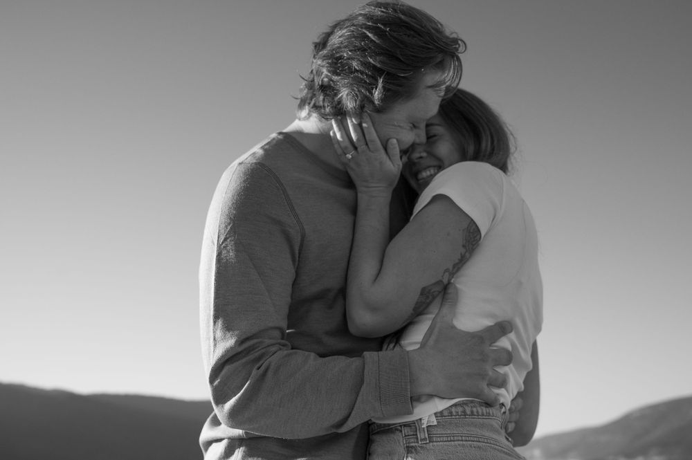 Black and white portrait of couple sharing intimate moment in outdoor setting.
