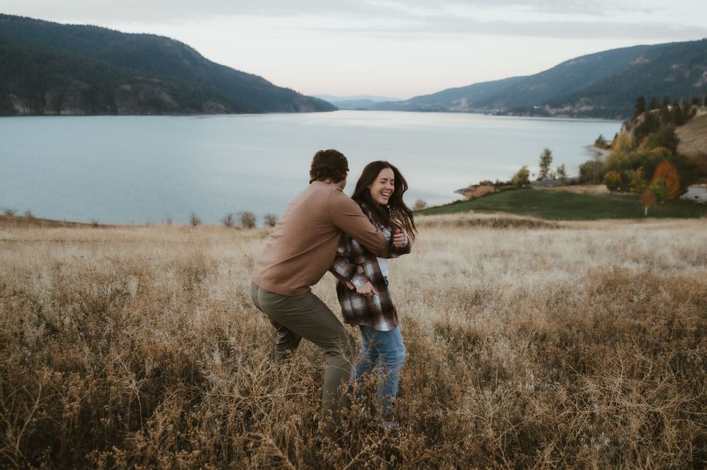 Playful dancing in tall autumn grass with mountain lake vista behind.