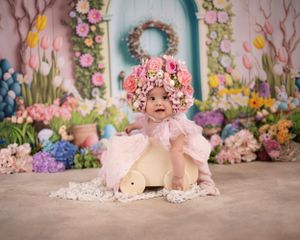 Floral backdrop with pink tulle dress and teddy bear against pastel spring flowers and teal wreath on wall.