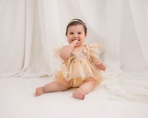 Baby in peach tulle dress photographed against white studio backdrop.