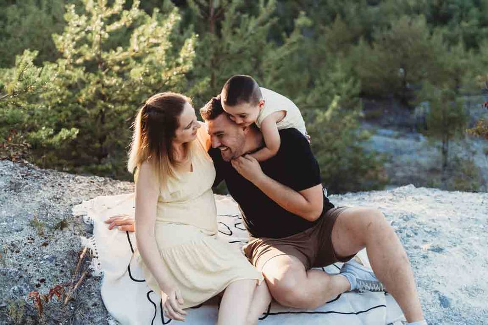 Couple shares an intimate moment while sitting together on a blanket outdoors during golden hour.
