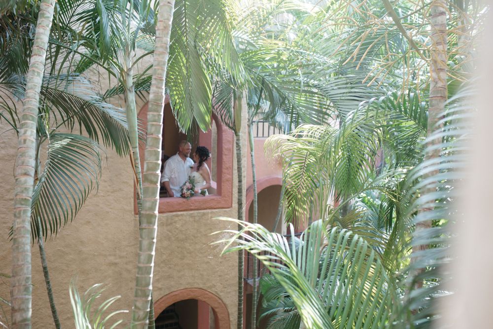 Lush tropical palm trees surround a rustic terrace with Southwestern architecture in a tranquil courtyard setting.