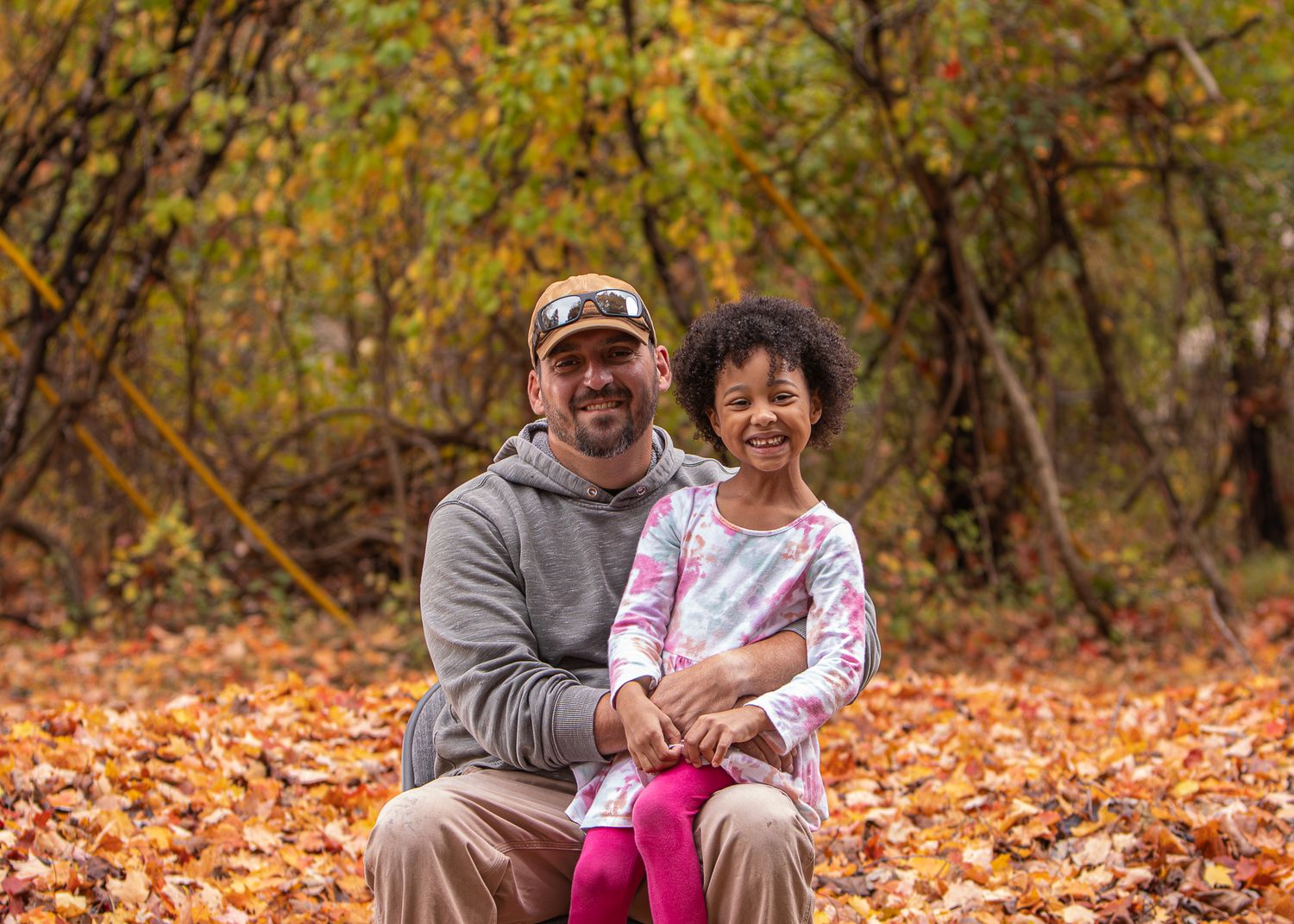 Family portrait session outdoors with everyone sitting along a large tree trunk.