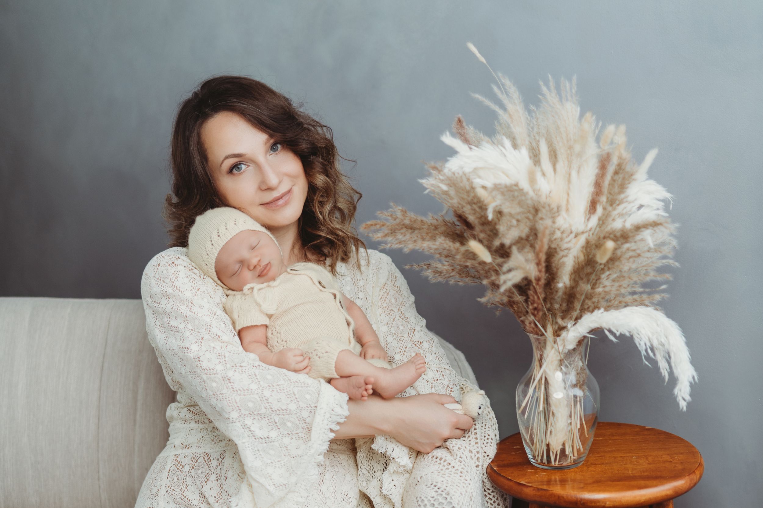 A tender moment captured in a cozy setting with white lace, soft lighting, and decorative pampas grass in a vase. | Bellevue, WA