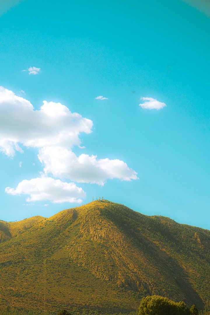 Mountain peak rising against turquoise sky with scattered white clouds in the southwest.