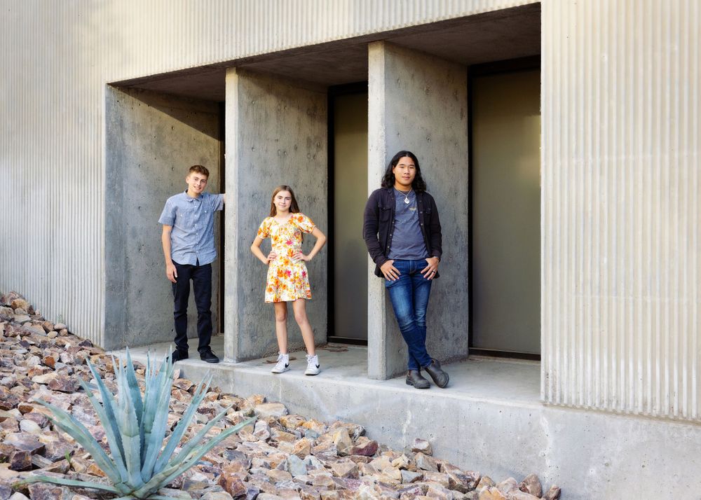 Three teen siblings stand in concrete alcoves with desert landscaping and an agave plant in the foreground at the Tucson Museum of Art.