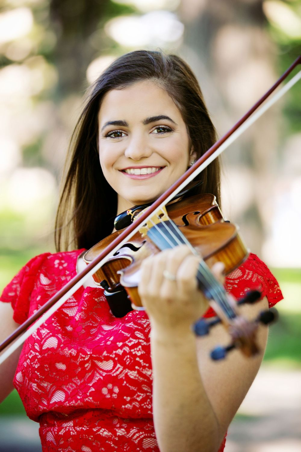 High school senior portrait taken at the University of Michigan Law Quad.  Half length portrait of a woman in a red dress playing the violin
