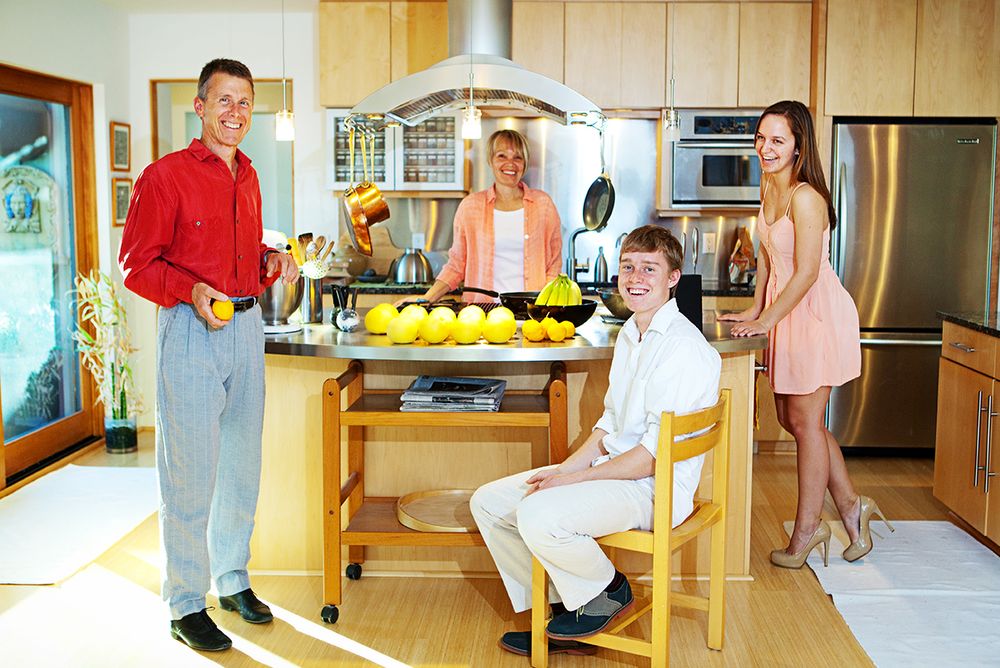 Family members gather around a wooden kitchen island with fresh lemons and fruit in a modern Tucson home kitchen.