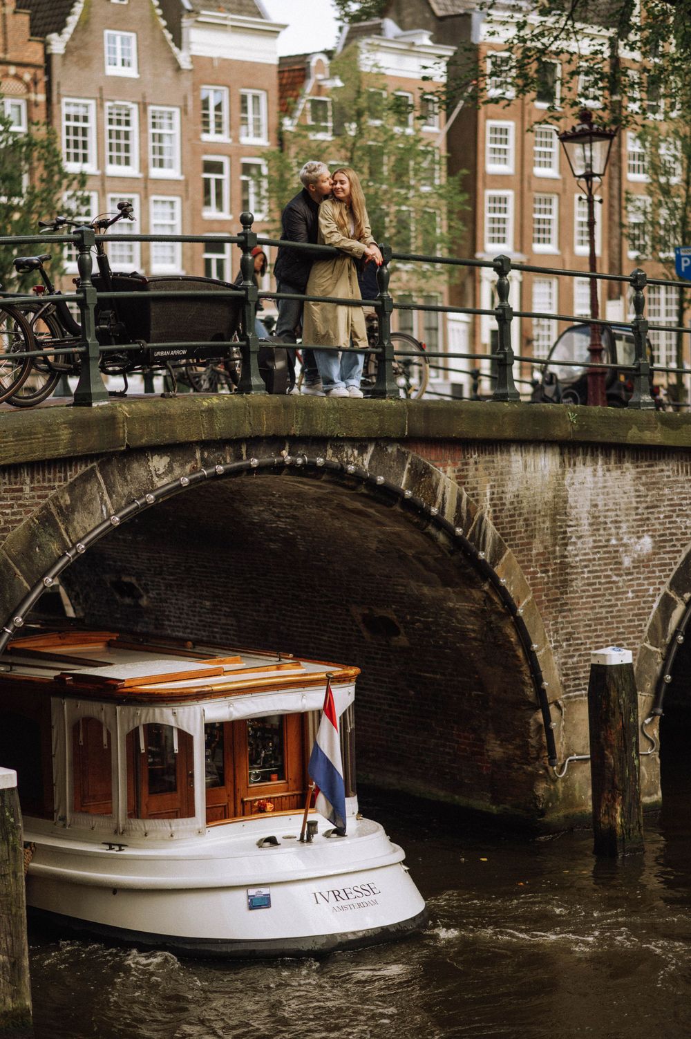 Tour boat passes under arched bridge in Amsterdam canal.