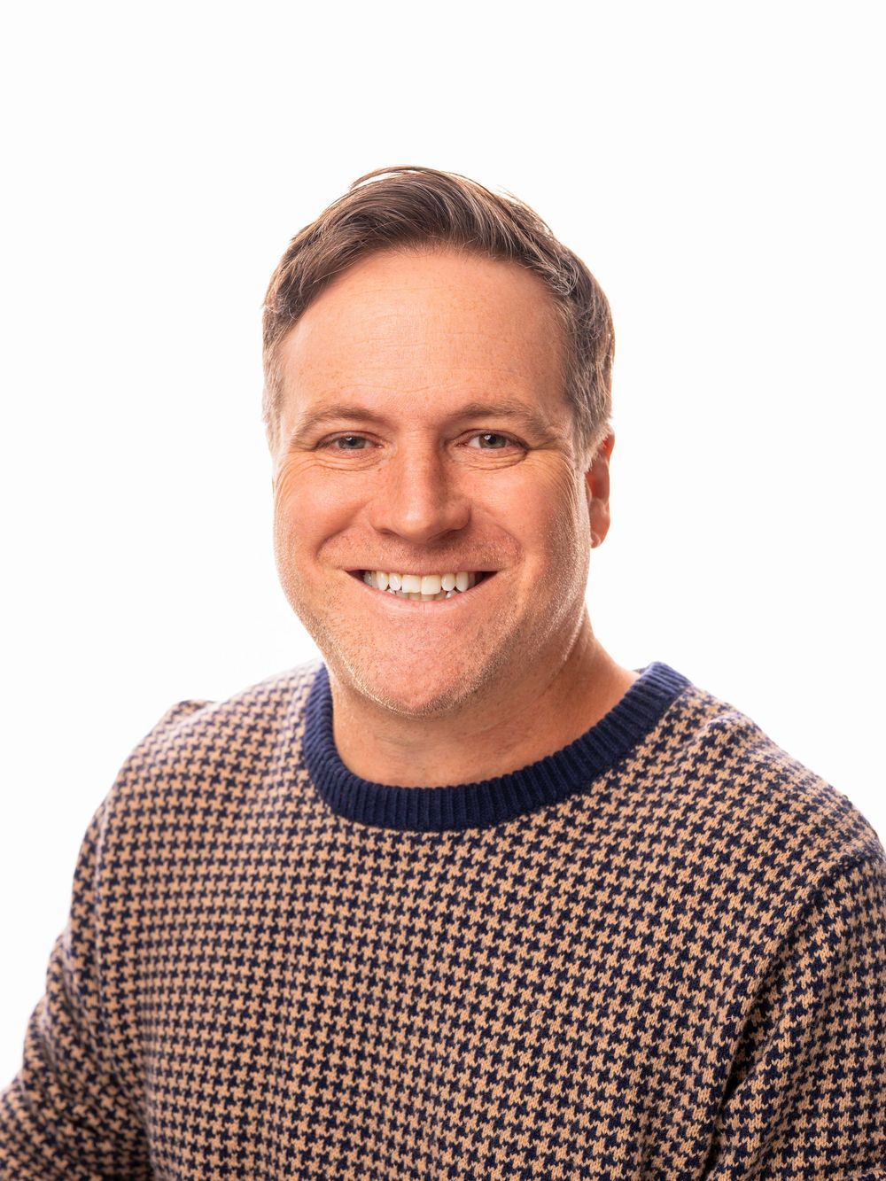A man wearing a brown and white houndstooth patterned sweater shows a range of natural expressions in three photos.