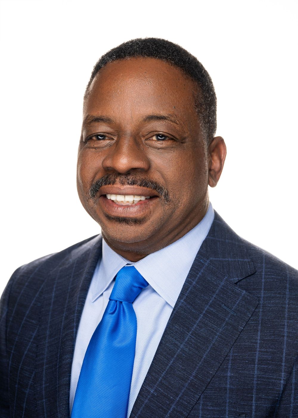 Professional headshot series showing a person in a navy pinstripe suit with bright blue tie against white background.