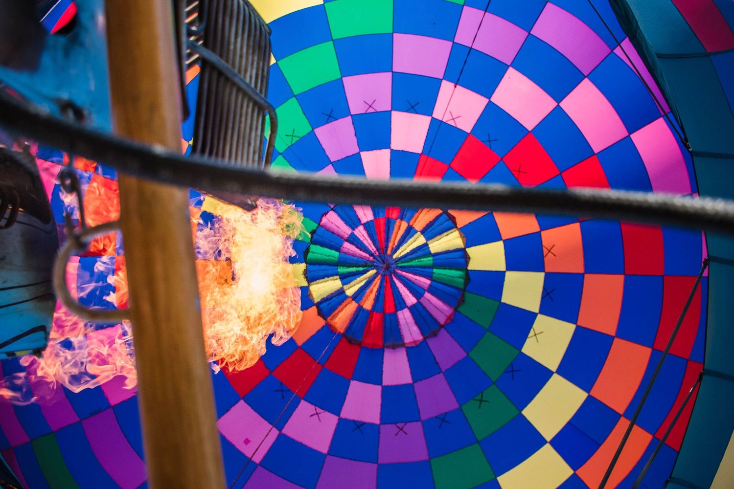 Close-up view of a vibrant hot air balloon interior showing colorful geometric patterns and flames.