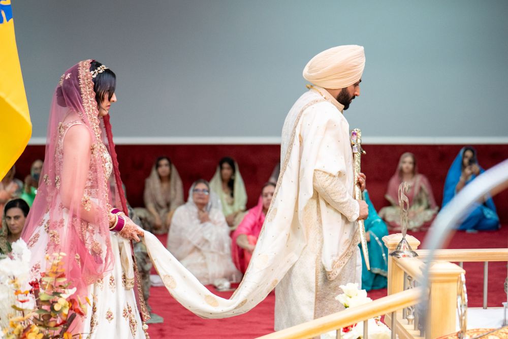 A traditional Sikh wedding ceremony with couple in cream and pink attire.