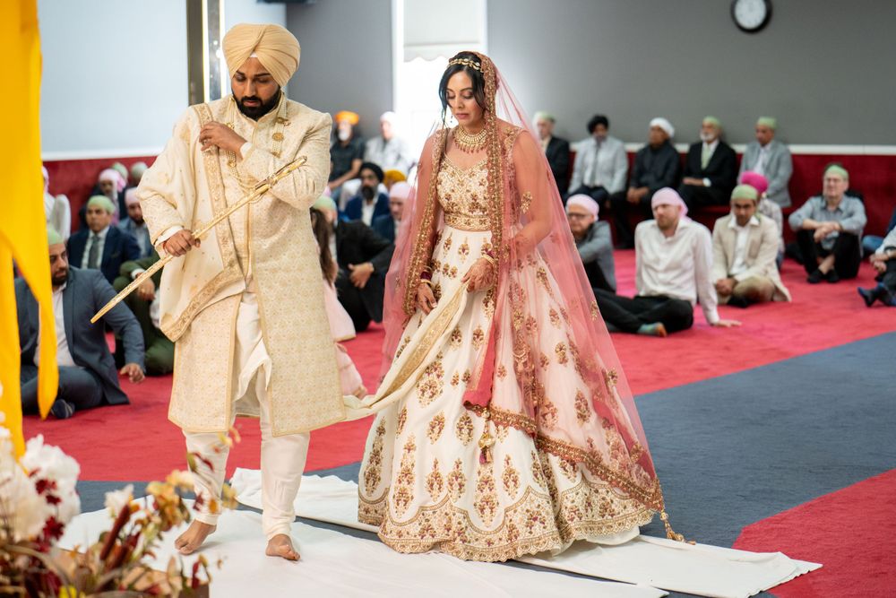 Newlyweds walking together in coordinated cream and pink traditional wedding attire.