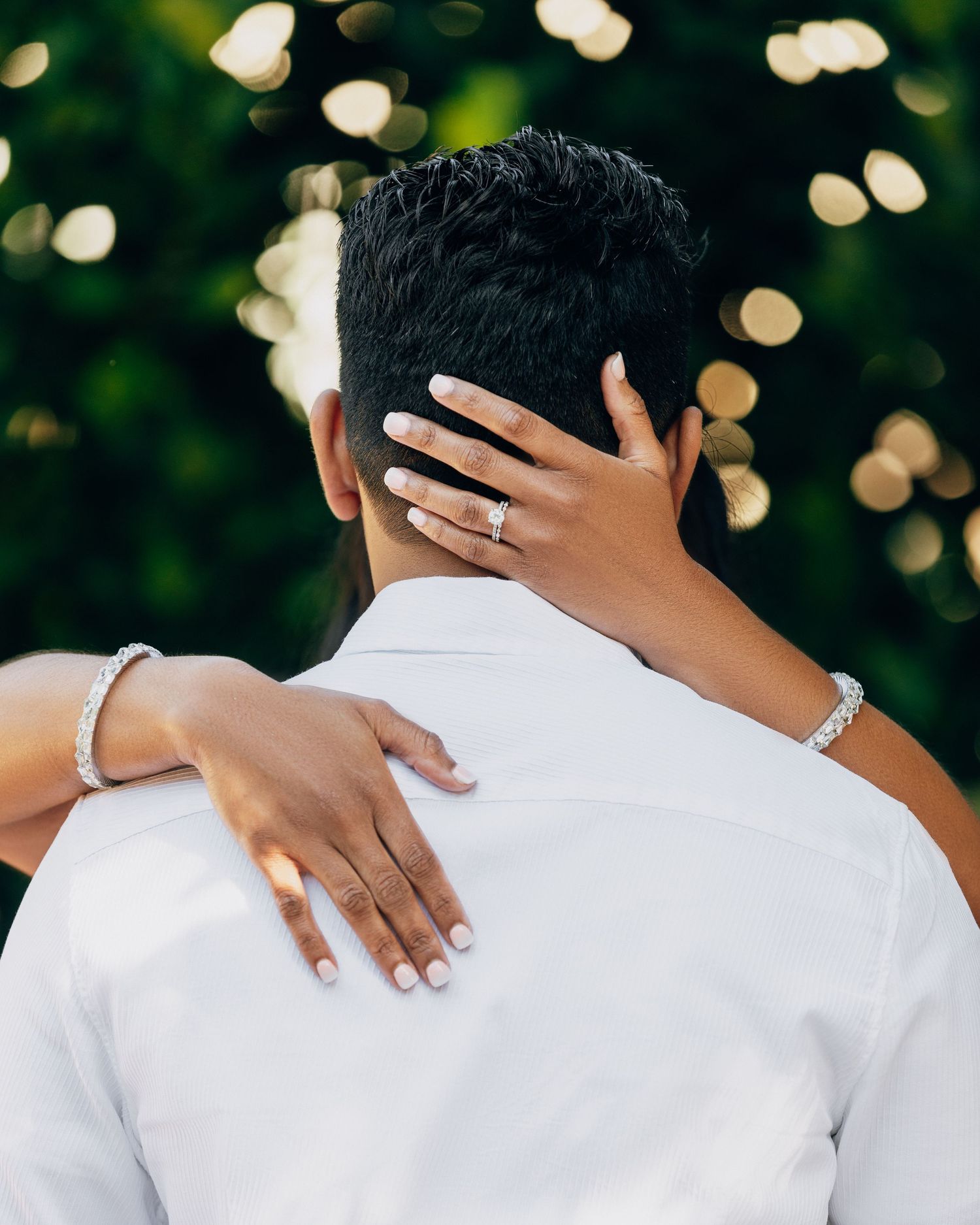 A close-up shot showing hands with jewelry embracing from behind.