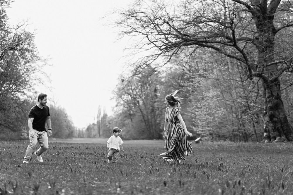 A joyful family plays together in a park on a sunny autumn day.
