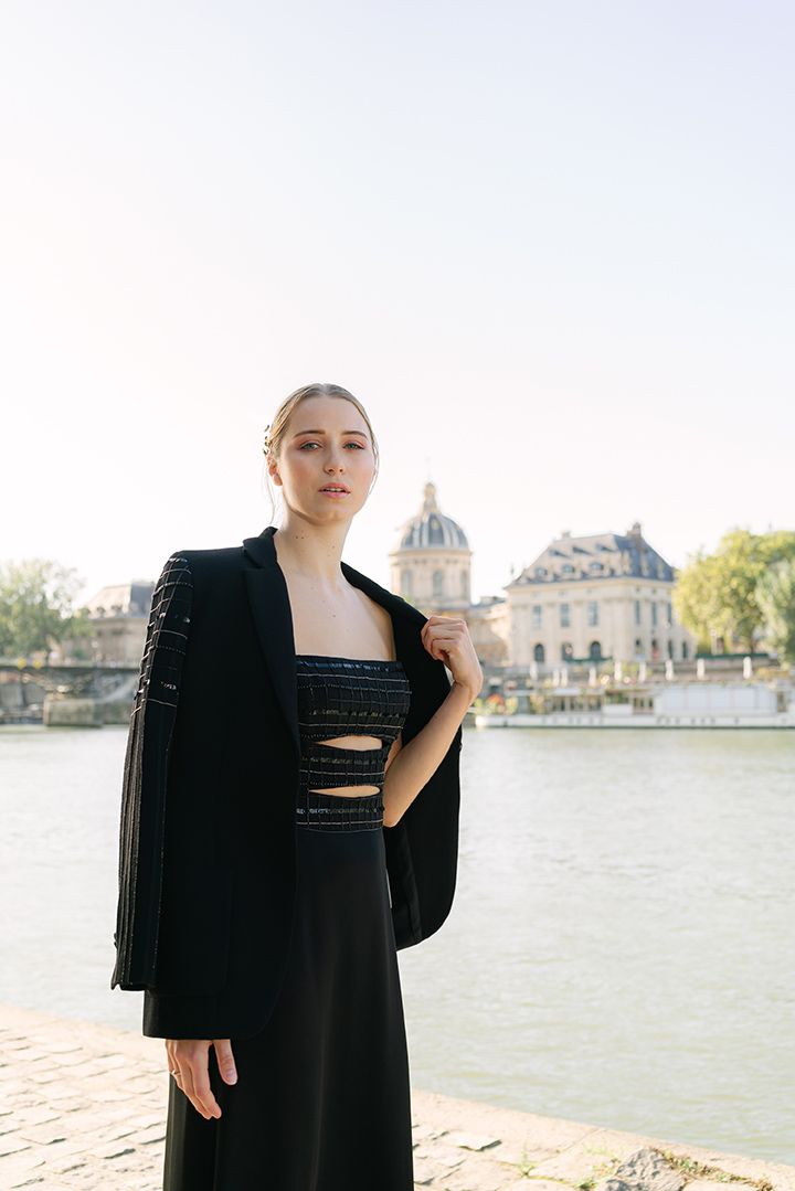 Elegant black evening dress with cutouts photographed by the Seine River in Paris.