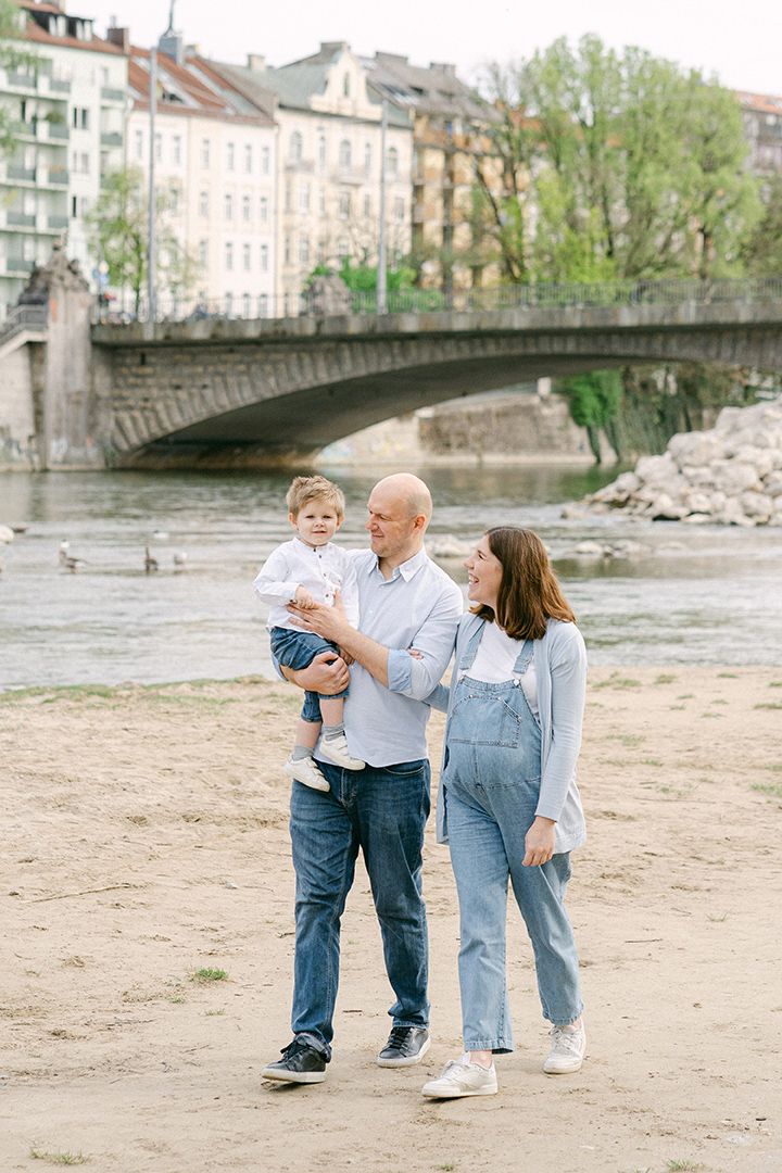 A family enjoying a stroll near a historic stone bridge in a European city setting.