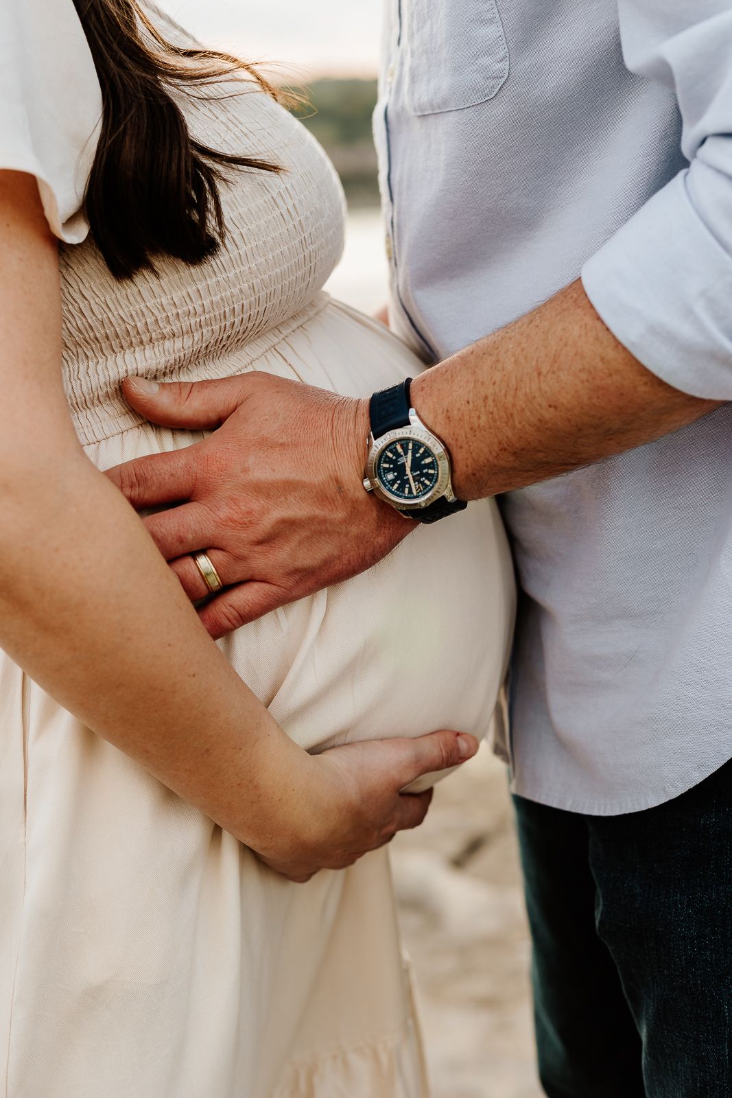 Parents’ hands on baby bump, captured by Austin family photographer in heartfelt maternity session