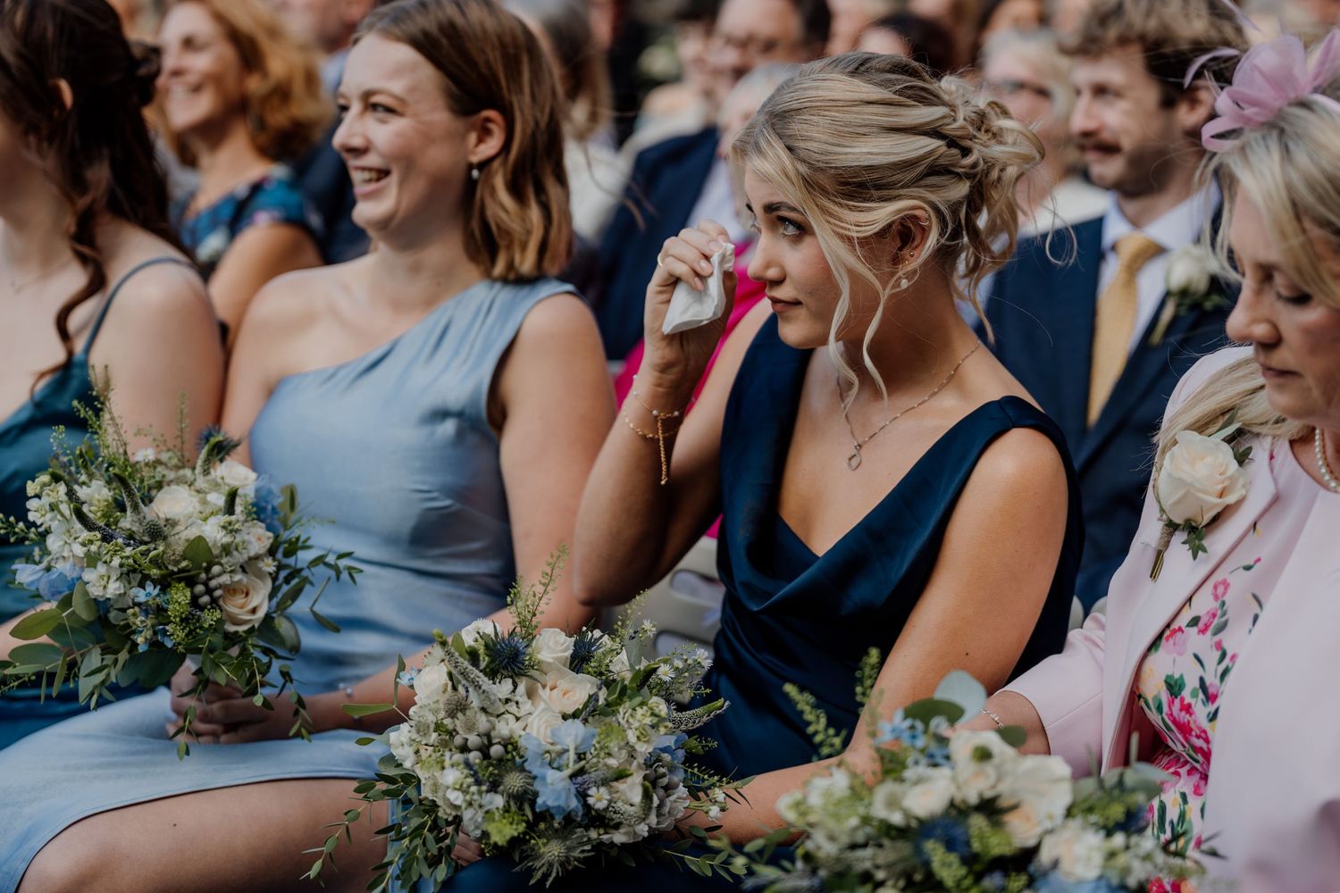 Wedding guests seated in rows of chairs watching an outdoor ceremony.