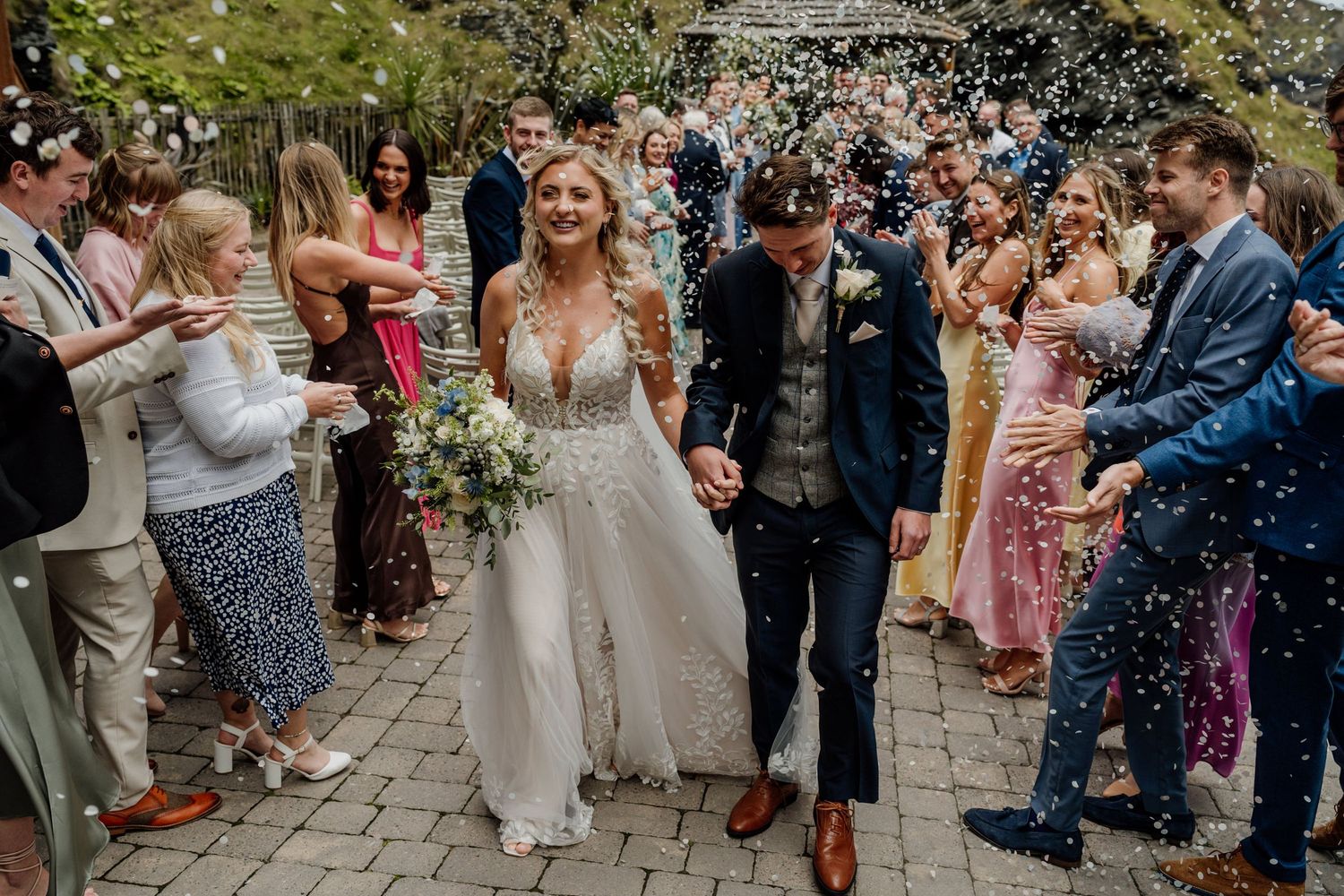 Wedding guests tossing confetti over a couple during their joyous celebration exit.