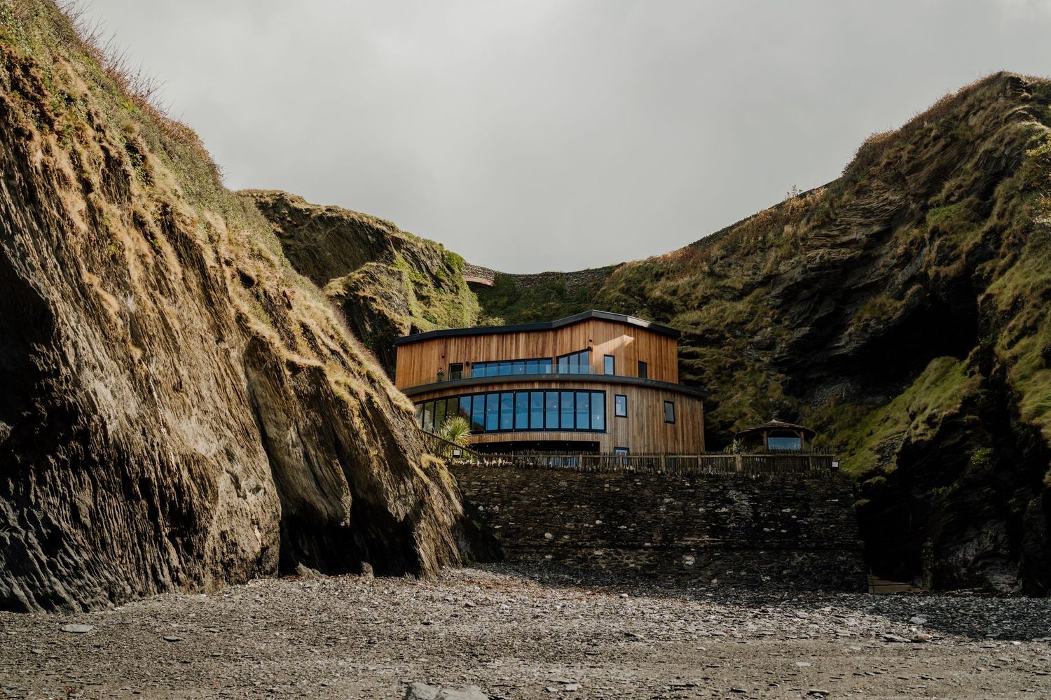 Panoramic view of a contemporary beach wedding venue surrounded by dramatic cliffs.